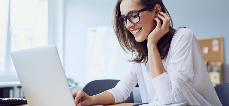 Une femme souriante en face de son ordinateur